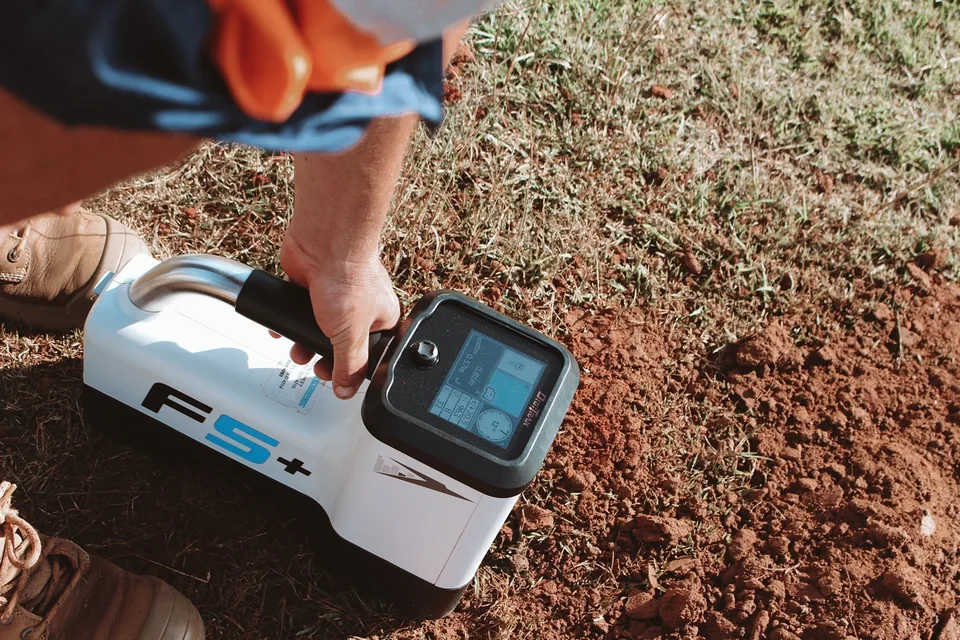 Crew member operating a handheld bore tracking receiver above the ground.