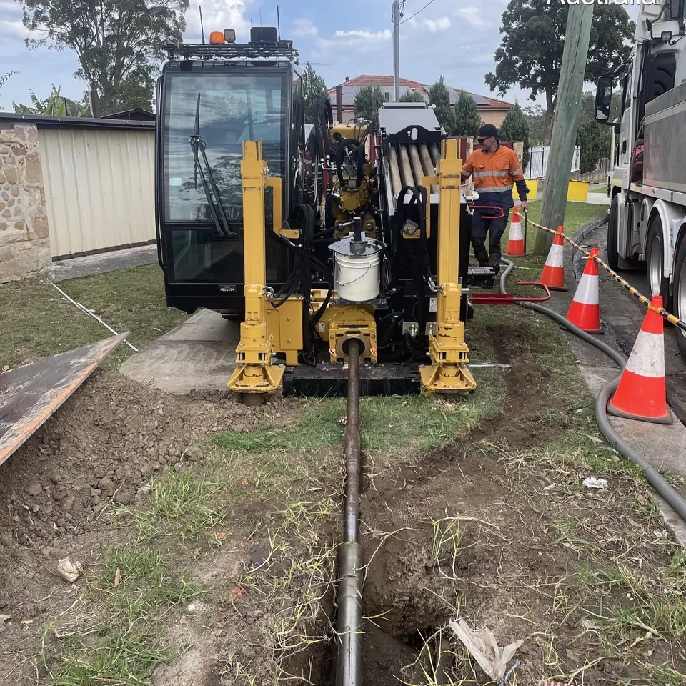 Directional drill operating in a marked work zone beside a footpath.