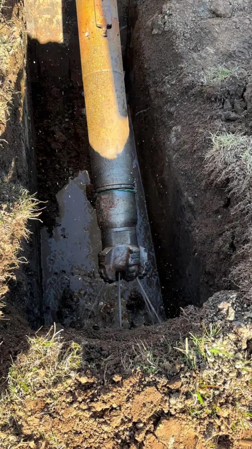 Drill rod and head at the bottom of a narrow excavated pit in Canberra, with water at the cutting head.