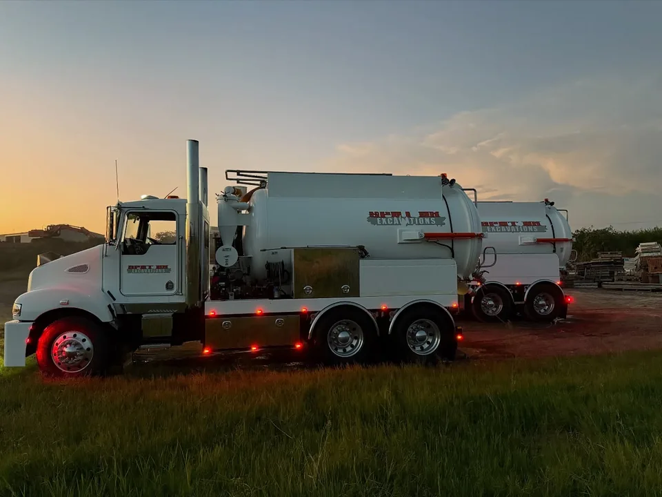 Spot On vacuum truck parked on grass at dusk.